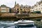 Tourists and residents on streets. The couple in boat floats on canal. Alesund, Norway