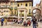 Tourists are resting sitting near the monument La Berlina - Tribuna o Capitello in the square Piazza Delle Erbe in Verona, Italy