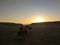 Tourists ride on a quad bike in the desert at sunset