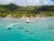 Tourists riding high speed jet boat in a stunning azure blue turquoise lagoon. Aerial view. Raiatea, French Polynesia.