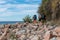Tourists on the rocky beach of the Baltic sea, travelers with backpacks walk on the rocks of the sea
