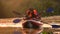 Tourists rowing oars in the canoe in the evening along the river. Slow motion