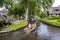 Tourists sailing on rented boats on the canal between houses in the famous village of Giethoorn. The village is called the Venice