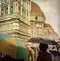 Tourists shelter beneath colorful umbrellas