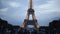 Tourists at shining Eiffel tower in evening. Action. Many tourists sit on lawn and enjoy beautiful view of shining