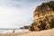 Tourists sightseeing sea caves on wonderful sandy beach with huge cliffs and rocks