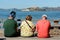 Tourists sitting on a bench with views of the island and Alcatraz prison in the background from Pier 39 in San Francisco
