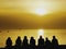 Tourists sitting on the seashore watching sunset