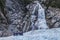 Tourists on snowy terrain with waterfall