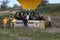 Tourists standing in the basket of a hot air balloon.