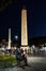 Tourists stroll past Egyptian obelisk