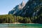Tourists swim in wooden boats on the Lago di Braies amid rocky mountains and forests. Braies lake in the Dolomites in