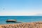 Tourists swimming sunbathing or doing other activities on the beach with large group of sunbeds and umbrellas