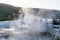 Tourists take photos of geysers on a boardwalk in Yellowstone National Park, partially obscured by