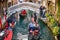 Tourists taking gondola, the traditional Venetian boat, on canal in Venice, Italy