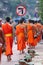 Tourists taking photos Laos Buddhist Monks with buddhist alms giving ceremony on the road in the morning, traditional of giving