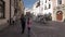 Tourists taking pictures of carriage with two white horses passing