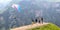 Tourists on top of a mountain pass, taking pictures of a flying paraglider