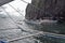 Tourists on traditional Philippino fisherman boats crossing the waters near grey and green limestone cliffs on a cloudy day of El