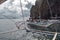 Tourists on traditional Philippino fisherman boats crossing the waters near grey limestone cliffs on a cloudy day of El Nido at