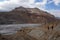 Tourists with trekking chopsticks walk along the Kali Gandaki River against the backdrop of the Chhusang cliffs.