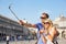 Tourists using selfie stick to make photo with smartphone