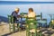 Tourists and visitors enjoy the Greek cuisine sitting on a table next to the sea in Koroni Town, Greece