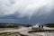 Tourists walk along the boardwalk of Black Sand Geyser Basin, unaware of a funnel cloud