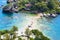 Tourists walk along narrow path surrounded by azure waters that connects Isola Bella to mainland Taormina, Sicily, Italy