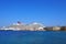 Tourists walk along the seafront at rhodes town harbor with the cruise ship carnival vista moored near sailing boats