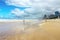 Tourists walk along wet beach by turbulent Pacific Ocean under stormy skies with tall towers of Surfers Paradise - Gold Coast Quee