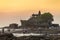 Tourists walk near the Tanah Lot temple during sunset in Bali