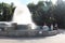 Tourists walk in the summer in the park by the fountain sprinkle water refreshes in the heat