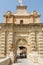 Tourists walking through Baroque portal of Mdina Gate