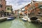 Tourists walking in Burano city streets and boats in the lagoon in beautiful city of Burano