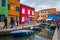 Tourists walking on Burano island street. Colorful houses in Venice, Italy. Travel destination concept to Italy