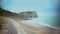 Tourists walking on coast near famous Etretat cliffs and enjoying beautiful view