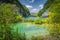 Tourists walking on footpath under tall cliff in a valley with lakes, Plitvice Lakes