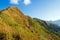 Tourists are walking on the mountain with golden meadows in the foreground and a blue sky background in Thong Pha Phum National