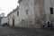 Tourists walking next to building with sculpted details on white walls, rust and stains on