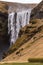 Tourists are walking up the track at the Skogafoss waterfall