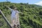 Tourists are walking on a wooden suspension bridge in the park of Yalong Bay Tropic