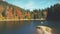 Tourists wander along lake sandy bank by mixed forests