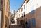 Tourists wander narrow shady streets between buildings of Medieval Mediterranean town Gruissan, France.