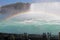 Tourists watch Niagara Falls tour boat under a full rainbow