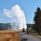 Tourists watching an eruption of Old Faithful Geyser from path,