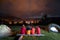 Tourists watching fire together beside camp and tents in dark