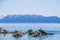 Tourists in water on paddleboards and climbing on rocks in blue Lake Tahoe with snow tipped mountains in distance