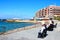 Tourists on waterfront benches, Marsalforn.