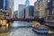 Tourists on white boat on Chicago canal on sunny summer day with skyscrapers on either side